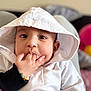 baby, child, hoodie, white_clothing, hand, fingers, face, cute, portrait, indoors, sitting, bracelet, expression, young, person, skin, eyes, candid, soft_light, closeup