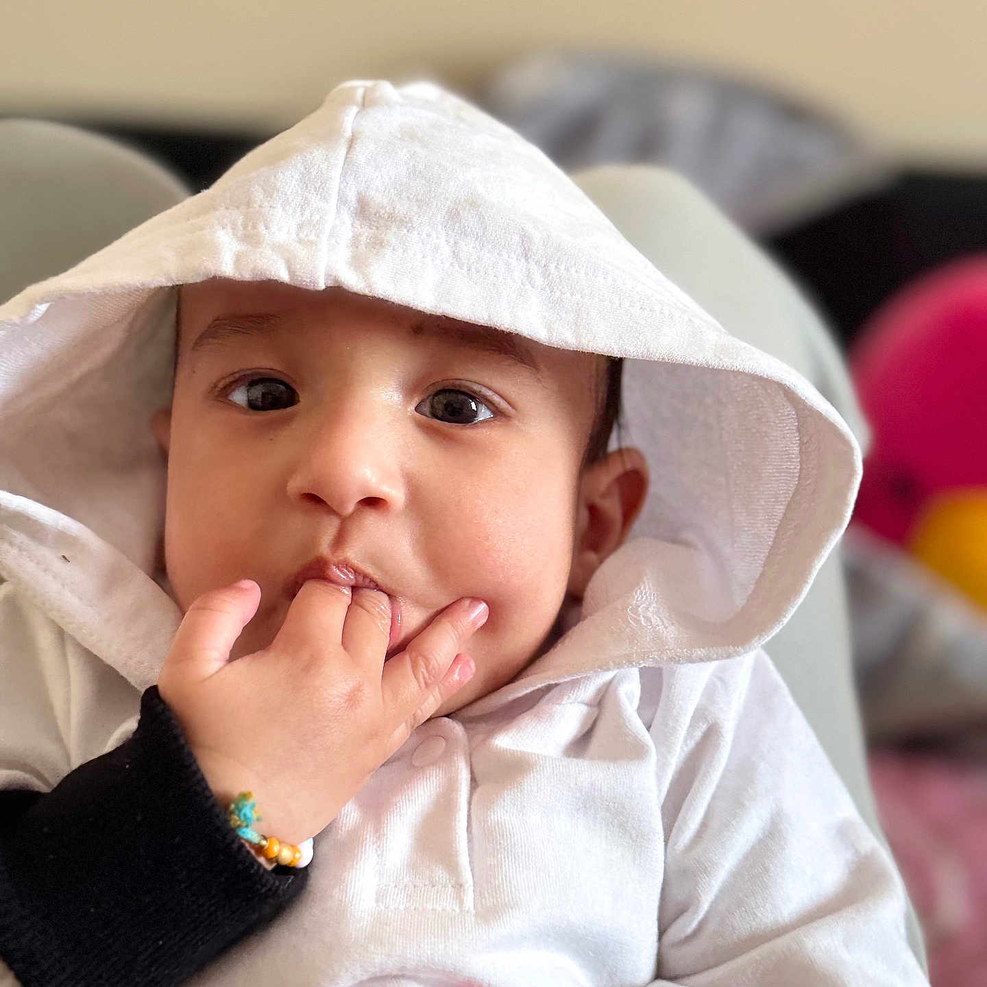 Ikmaan Singh is registered to the contest to win money with this photo: baby, bracelet, candid, child, closeup, cute, expression, eyes, face, fingers, hand, hoodie, indoors, person, portrait, sitting, skin, soft_light, white_clothing, young