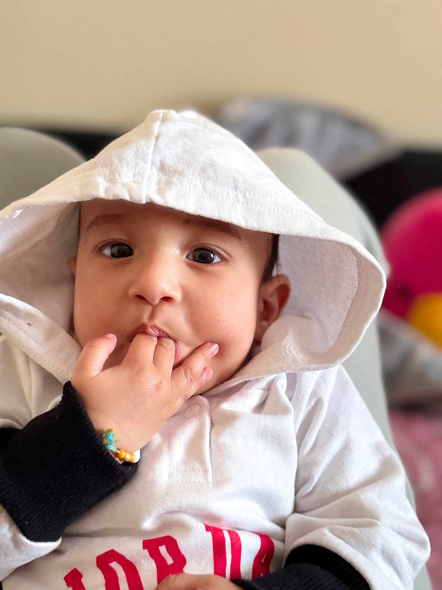 Ikmaan Singh is registered to the contest to win money with this photo: baby, child, hoodie, white_clothing, hand, fingers, face, cute, portrait, indoors, sitting, bracelet, expression, young, person, skin, eyes, candid, soft_light, closeup