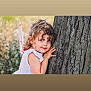 child, girl, curly_hair, blue_eyes, tree, fairy_wings, outdoor, nature, playing, smiling, cute, portrait, costume, whimsical, childhood, innocence, summer, daylight, happy, fun