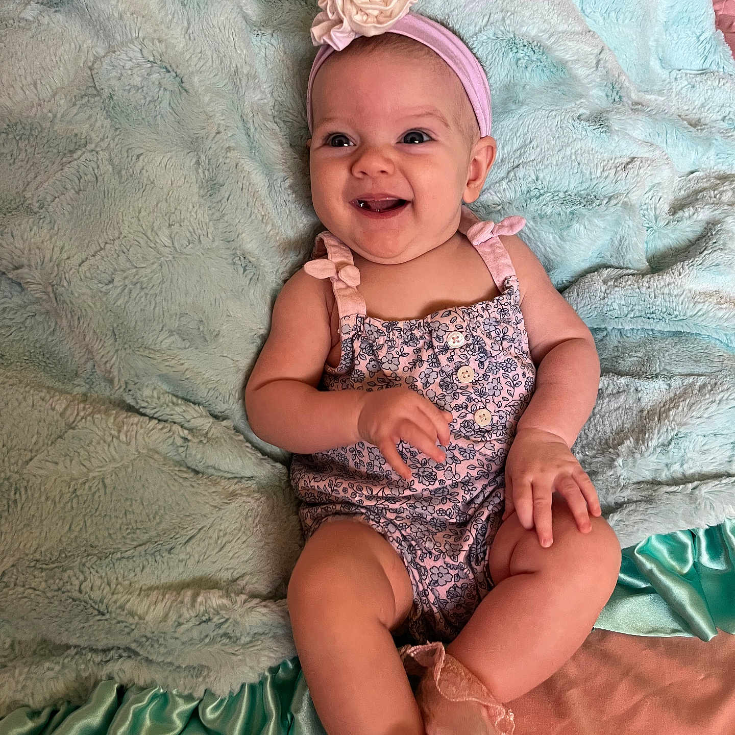 Maury Mckenzie joined the competition — help win amazing prizes! baby, child, smiling, headband, flower, blanket, sitting, romper, pink, blue, soft_texture, happy, cute, infant, portrait, indoors, sock, clothing, fabric, person