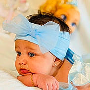 Indira joined the competition — help win amazing prizes! baby, blue_bow, headband, infant, child, portrait, closeup, soft_lighting, doll, blue_eyes, cute, resting, hand, bracelet, silk, fabric, indoor, skin, young_child, face