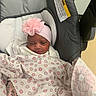 newborn, baby, infant, child, face, headband, flower, pink, blanket, polka_dot, car_seat, padded_seat, sleeping, awake, portrait, indoors, tattoo, adult_arm, hospital, cozy