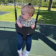 Ember is registered to the contest to win money with this photo: toddler, child, swing, playground, outdoor, grass, trees, blue_sky, clouds, black_swing_seat, shoes, leggings, short_sleeve_shirt, hair_bow, daylight, shadow, happy, park, fence, bench