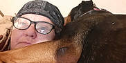 Boo Boo is registered to the contest to win money with this photo: person, dog, glasses, bandana, indoor, closeup, face, ear, brown, black, skin, portrait, cozy, snuggle, pet, companion, casual, headwear, relaxed, human