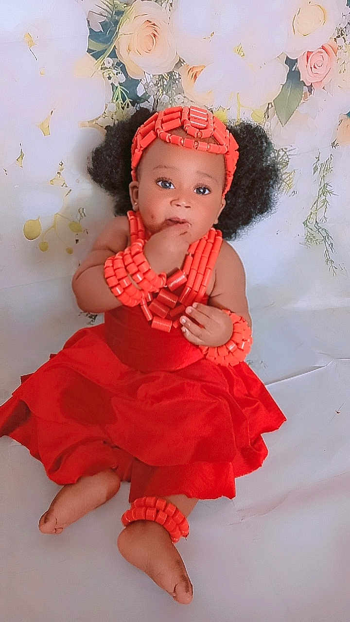 Merry participe au concours pour gagner de l'argent avec cette photo : accessories, anklet, baby, beads, bracelets, child, curly_hair, cute, feet, flower_background, hands, headband, indoor, innocent, portrait, red_dress, sitting, skin, traditional_clothing, young_child