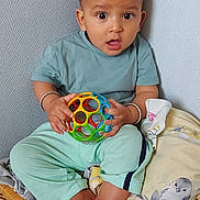 Pragyan a rejoint le concours — aidez-le/la à gagner de superbes lots ! baby, child, toy, ball, wicker_basket, blanket, indoor, curious, wide_eyes, sitting, clothing, foot, hand, person, cute, playful, soft_lighting, expression, casual, home