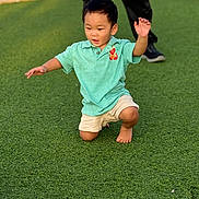 Naniko is registered to the contest to win money with this photo: child, boy, grass, outdoor, polo_shirt, shorts, barefoot, green, playing, fun, sunlight, person, kneeling, casual_clothing, daytime, park, happy, movement, adult, background