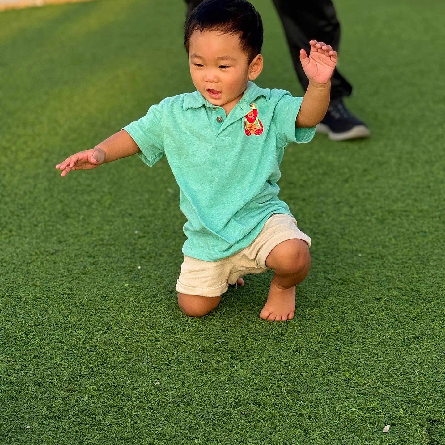 Naniko is registered to the contest to win money with this photo: child, boy, grass, outdoor, polo_shirt, shorts, barefoot, green, playing, fun, sunlight, person, kneeling, casual_clothing, daytime, park, happy, movement, adult, background