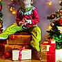 Kaden is registered to the contest to win money with this photo: child, toddler, holiday, christmas, pajamas, presents, gift, string_lights, decorations, tree, wooden_box, floor, indoors, festive, red, green, yellow, face, person, celebration