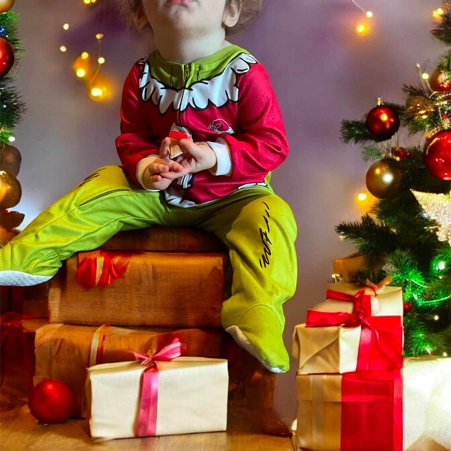 Kaden is registered to the contest to win money with this photo: celebration, child, christmas, decorations, face, festive, floor, gift, green, holiday, indoors, pajamas, person, presents, red, string_lights, toddler, tree, wooden_box, yellow