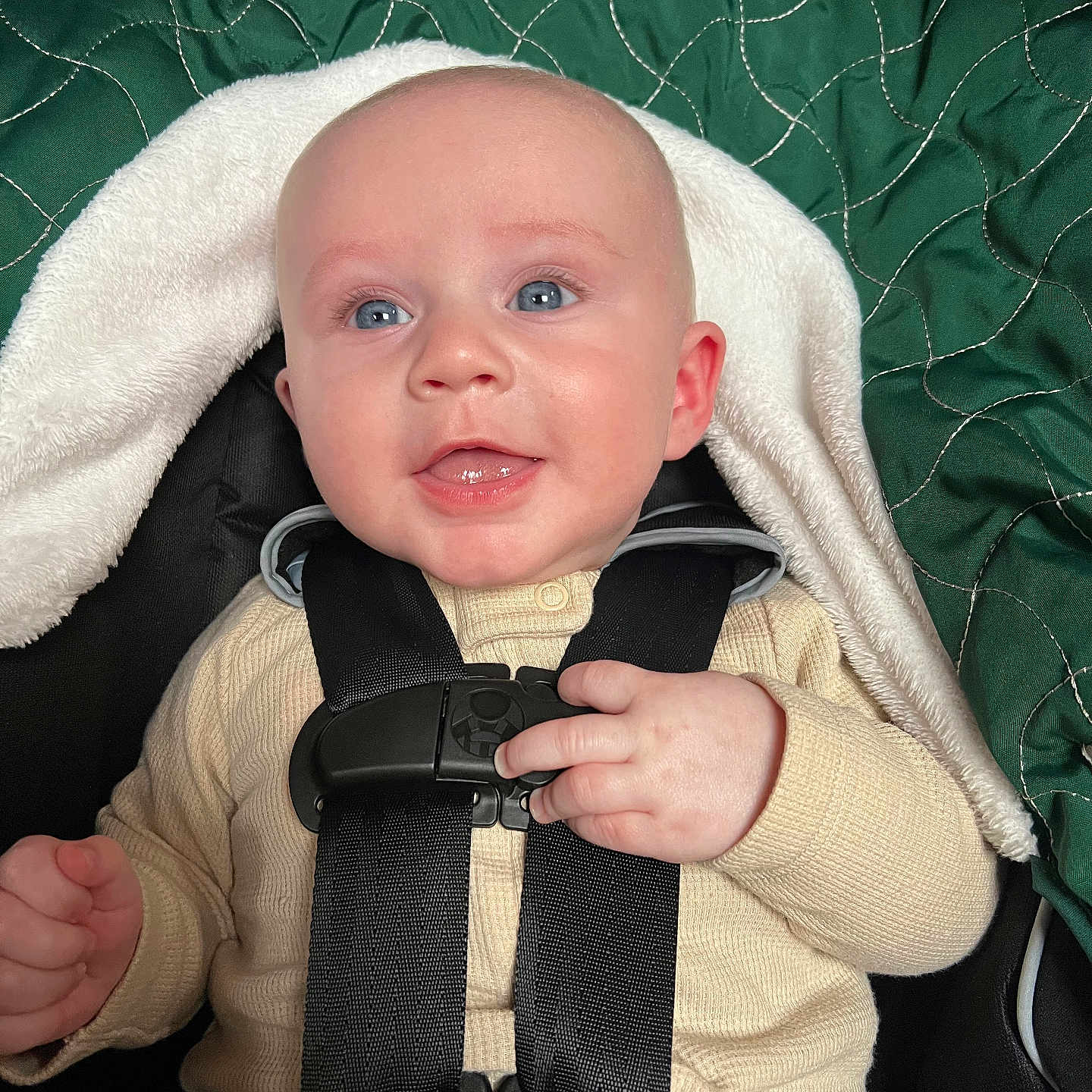 Lincoln is registered to the contest to win money with this photo: baby, child, car_seat, blue_eyes, smiling, cream_outfit, green_blanket, quilted, straps, sitting, infant, cute, happy, indoors, portrait, young_child, cozy, hand, face, apparel