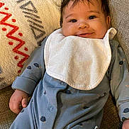 Weston joined the competition — help win amazing prizes! baby, infant, smile, onesie, bib, couch, pillow, turtle_print, happy, child, indoor, cozy, cute, face, person, sitting, relaxed, home, comfort, young