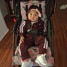 Kurakura is registered to the contest to win money with this photo: toddler, child, stroller, tracksuit, headband, indoor, wooden_floor, shoes, white_sneakers, pink_bow, baby, seat_belt, patterned_fabric, person, young_child, casual_clothing, flooring, cute, curious, sitting