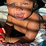 Kahlani joined the competition — help win amazing prizes! baby, blanket, blue, child, cute, expression, eyes, face, hand, indoor, infant, person, playful, red, remote_control, shadow, skin, smiling, sunlight, toy