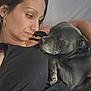 affection, animal, black_clothing, black_dog, bond, casual, close_up, cuddle, dog, earrings, face, human, indoor, love, pet, portrait, relaxation, resting, skin, woman