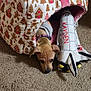 Athena is registered to the contest to win money with this photo: puppy, dog, pet_bed, plush_toy, space_shuttle, gingerbread_pattern, carpet, indoor, cozy, cute, snuggling, animal, young_dog, fabric, toy, home, brown, pink, collar, small_dog