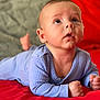 Damir participe au concours pour gagner de l'argent avec cette photo : baby, infant, blue_clothing, red_blanket, lying_down, face, hands, curious, looking_up, skin, head, indoors, soft_texture, cozy, child, person, expression, young, portrait, toddler