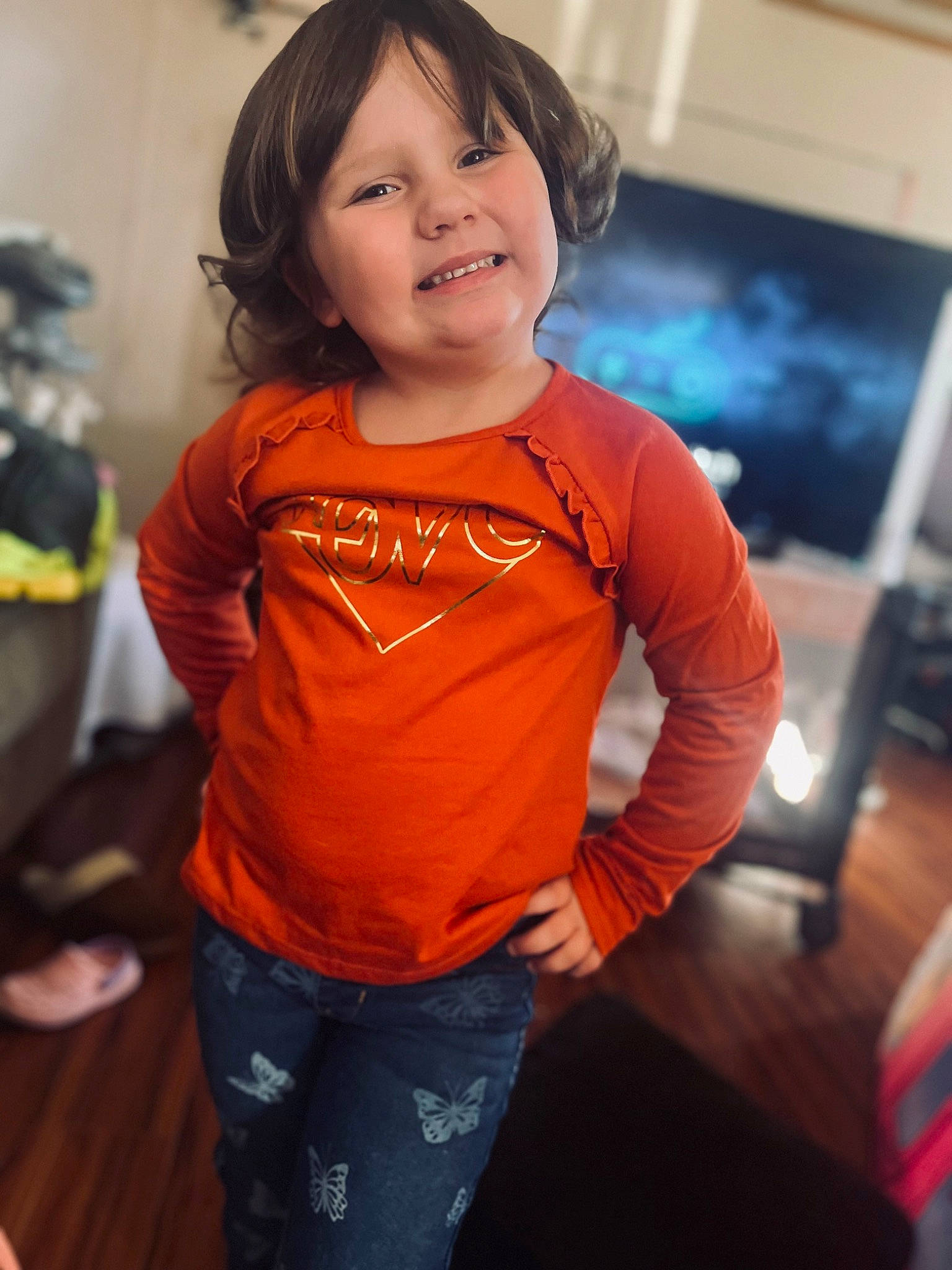 Melissa Phipps is registered to the contest to win money with this photo: abdomen, brown_hair, child, denim, eye, flooring, fun, happy, iris, joy, long_sleeved_t_shirt, neck, person, picture_frame, sleeve, smile, standing, t_shirt, toddler, trunk