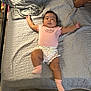 Abigail Ortuno is registered to the contest to win money with this photo: baby, infant, lying_down, pink_clothing, socks, blanket, quilt, bed, floor, hand, phone, person, indoor, cute, relaxed, texture, footwear, sleepwear, cozy, home