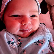 Emery is registered to the contest to win money with this photo: baby, infant, face, smile, hat, clothing, floral_pattern, closeup, cute, child, skin, eyes, cheeks, portrait, warm_lighting, newborn, person, soft_texture, indoors, happy