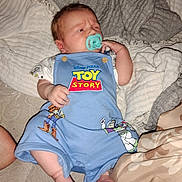 Jase Jr joined the competition — help win amazing prizes! baby, newborn, pacifier, toy_story, clothing, blue_romper, blanket, infant, cute, sleepwear, foot, hand, lying_down, indoor, person, child, soft_texture, expression, resting, cozy