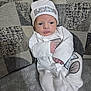 baby, newborn, infant, white_clothing, hat, couch, fabric, texture, indoors, portrait, child, small_hands, sleepwear, cozy, soft, cute, babies, resting, seated, home