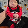 Lake is registered to the contest to win money with this photo: newborn, baby, sleeping, infant, hand, clothing, hat, booties, red, black, person, portrait, indoors, blanket, halloween, pumpkin, bat, spider_web, cute, resting