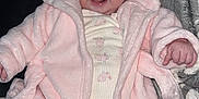 Mabel is registered to the contest to win money with this photo: baby, child, infant, pink_jacket, hooded_clothing, smiling, happy, blanket, patterned_blanket, cozy, cute, sitting, indoors, warm_clothing, face, portrait, small_hands, onesie, soft_texture, playful