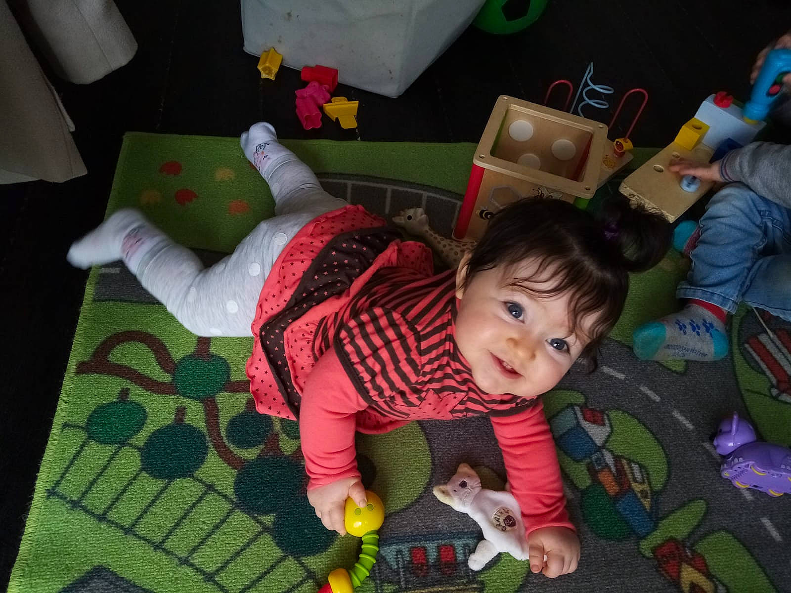 Thalia participe au concours pour gagner de l'argent avec cette photo : baby, baby_products, baby_toddler_clothing, baby_toys, child, event, flooring, fun, green, happy, lap, person, play, room, sitting, smile, sock, stuffed_toy, textile, toddler