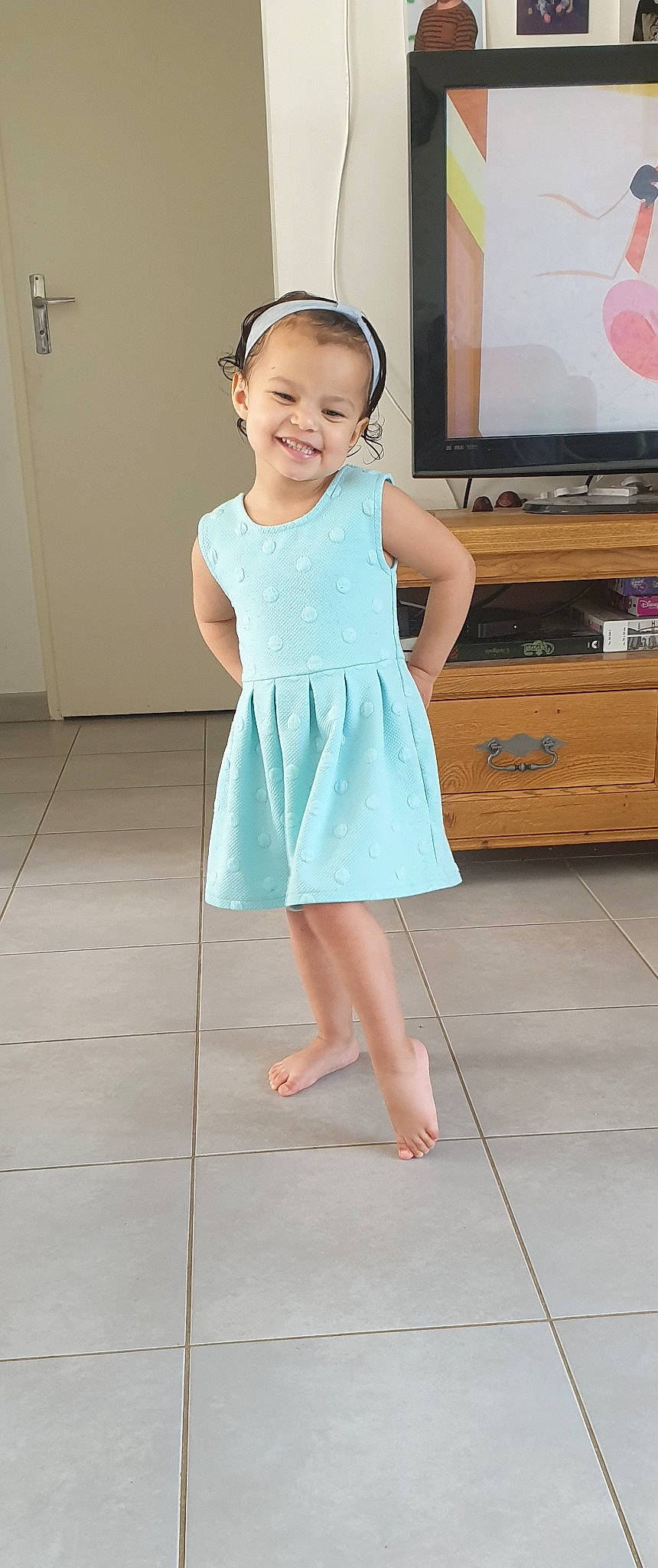 Mya participe au concours pour gagner de l'argent avec cette photo : arm, baby_toddler_clothing, day_dress, dress, floor, flooring, gesture, hair, hairstyle, happy, joy, leg, neck, one_piece_garment, person, pink, shoulder, skin, sleeve, smile