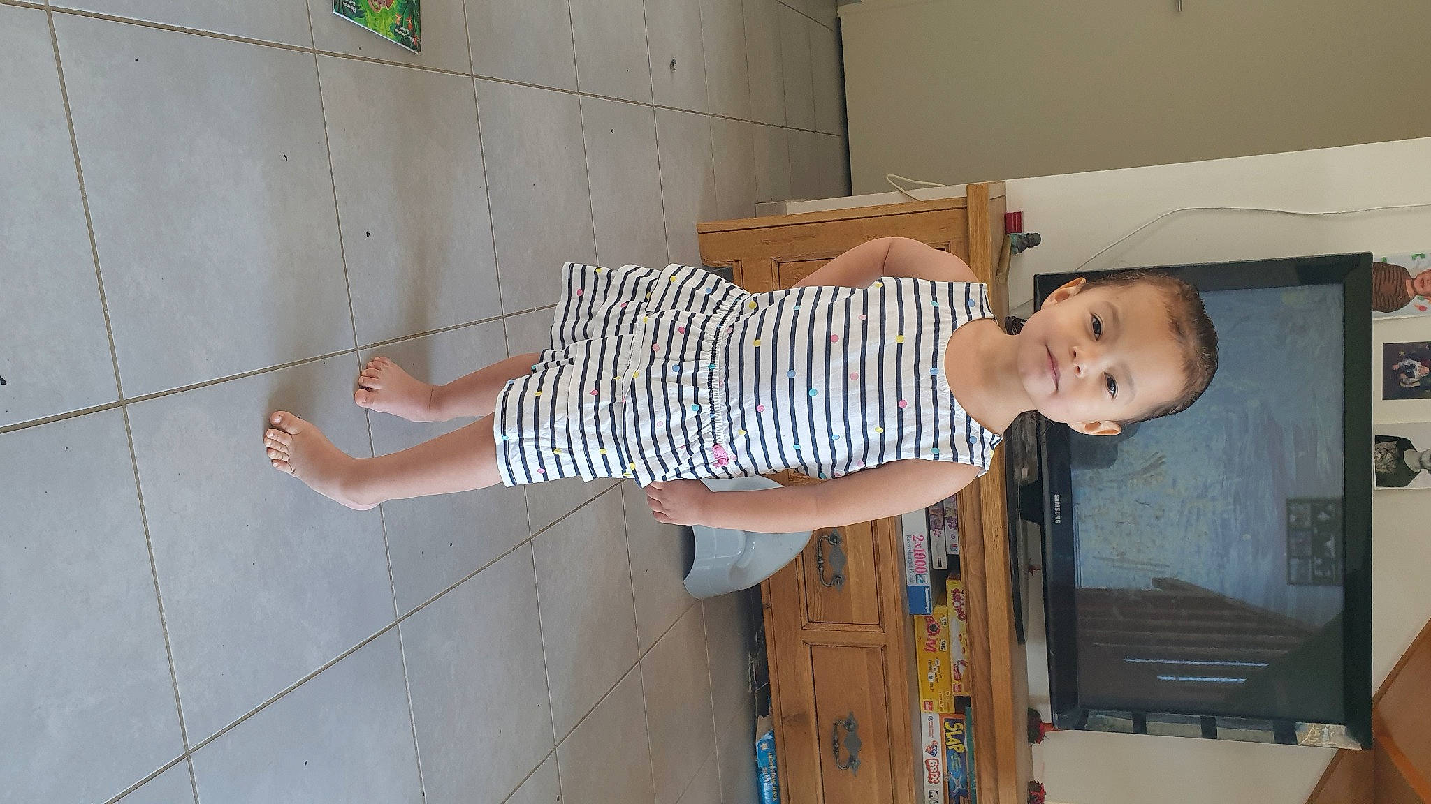 Mya participe au concours pour gagner de l'argent avec cette photo : baby, baby_toddler_clothing, child, door, elbow, flooring, foot, hardwood, human_leg, knee, pattern, person, room, smile, standing, street_fashion, t_shirt, thigh, toddler, waist