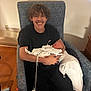 Ella is registered to the contest to win money with this photo: young_person, baby, smiling, armchair, blanket, indoor, wooden_floor, pillow, hospital, person, holding, sleeping, happy, clothing, face, mustache, black_clothing, medical_wires, furniture, portrait