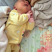 Ella is registered to the contest to win money with this photo: baby, sleeping, yellow_onesie, blanket, bed, floral_bedding, soft_texture, infant, cozy, pink_cuffs, polka_dots, child, peaceful, cute, resting, indoor, newborn, hands_clasped, portrait, fabric