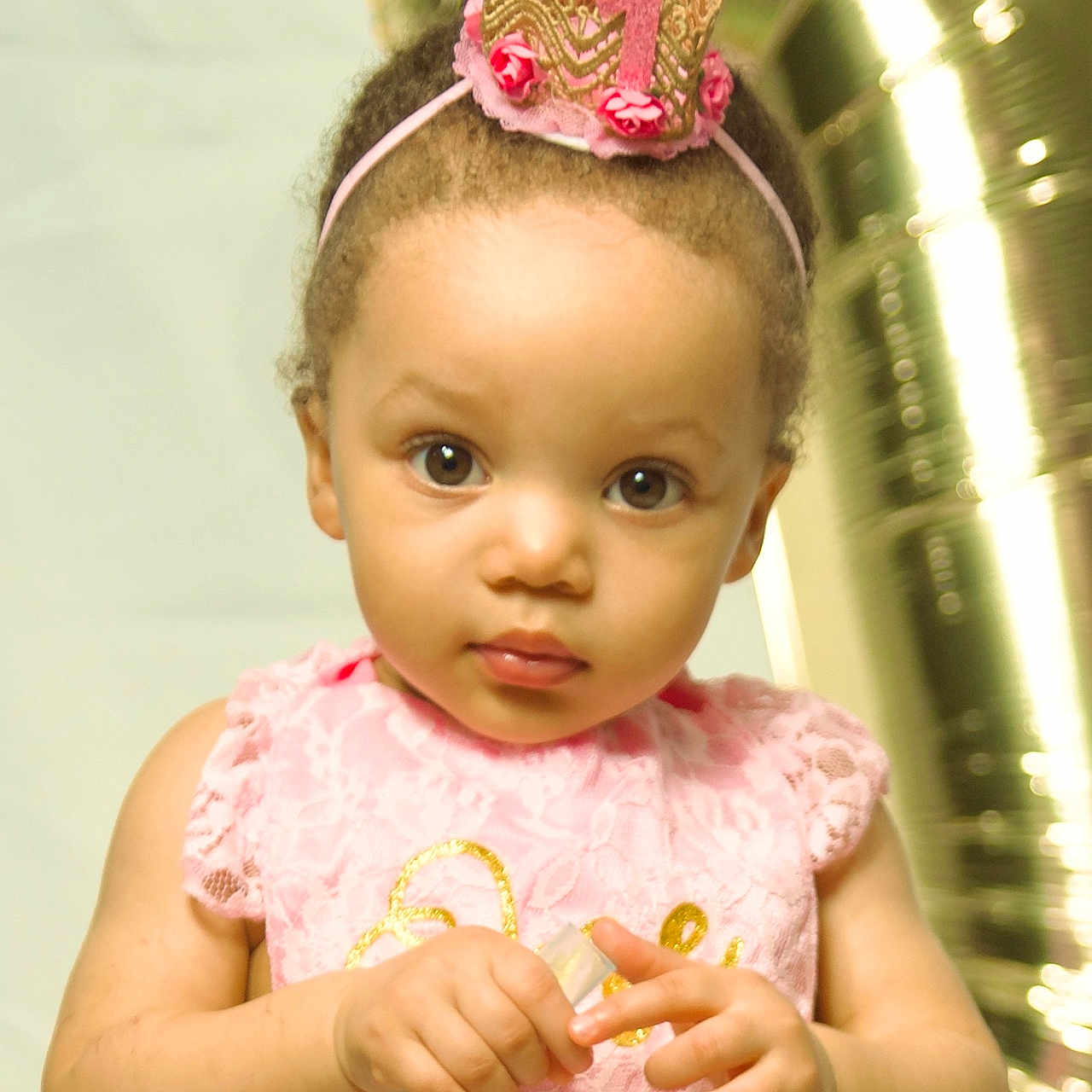 Shannon is registered to the contest to win money with this photo: baby, balloon, birthday, celebration, child, crown, curious, cute, event, face, headband, holding, indoor, lace, number_one, party, pink_dress, portrait, toddler, young_child