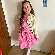Novalise Maldonado is registered to the contest to win money with this photo: child, girl, pink_dress, cardigan, smile, long_hair, indoor, floor, wall, door, footwear, white_tights, portrait, standing, happy, young, person, casual, home, light_switch