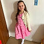 child, girl, pink_dress, cardigan, smile, long_hair, indoor, floor, wall, door, footwear, white_tights, portrait, standing, happy, young, person, casual, home, light_switch