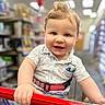baby, toddler, child, shopping_cart, smile, blue_eyes, clothing, shirt, hair, hand, grocery_store, aisle, blurred_background, indoor, happy, portrait, cute, person, retail, shopping