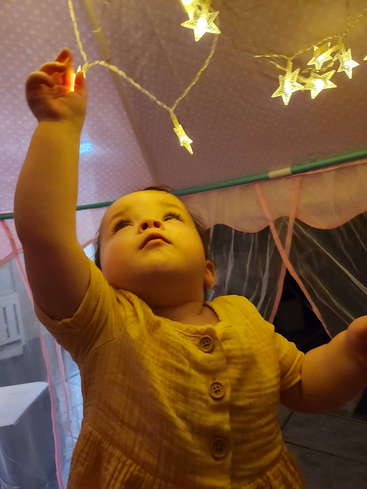 Lillian is registered to the contest to win money with this photo: arm, art, ceiling, child, event, flash_photography, fun, gesture, happy, human_body, light, lighting, organ, organism, party_supply, person, room, shoulder, thumb, toddler