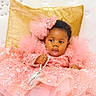 baby, child, pink_dress, sequins, tulle, purse, golden_cushion, white_background, sitting, curious_expression, adorable, footwear, headband, portrait, indoor, fashion, cute, celebration, luxury, fancy