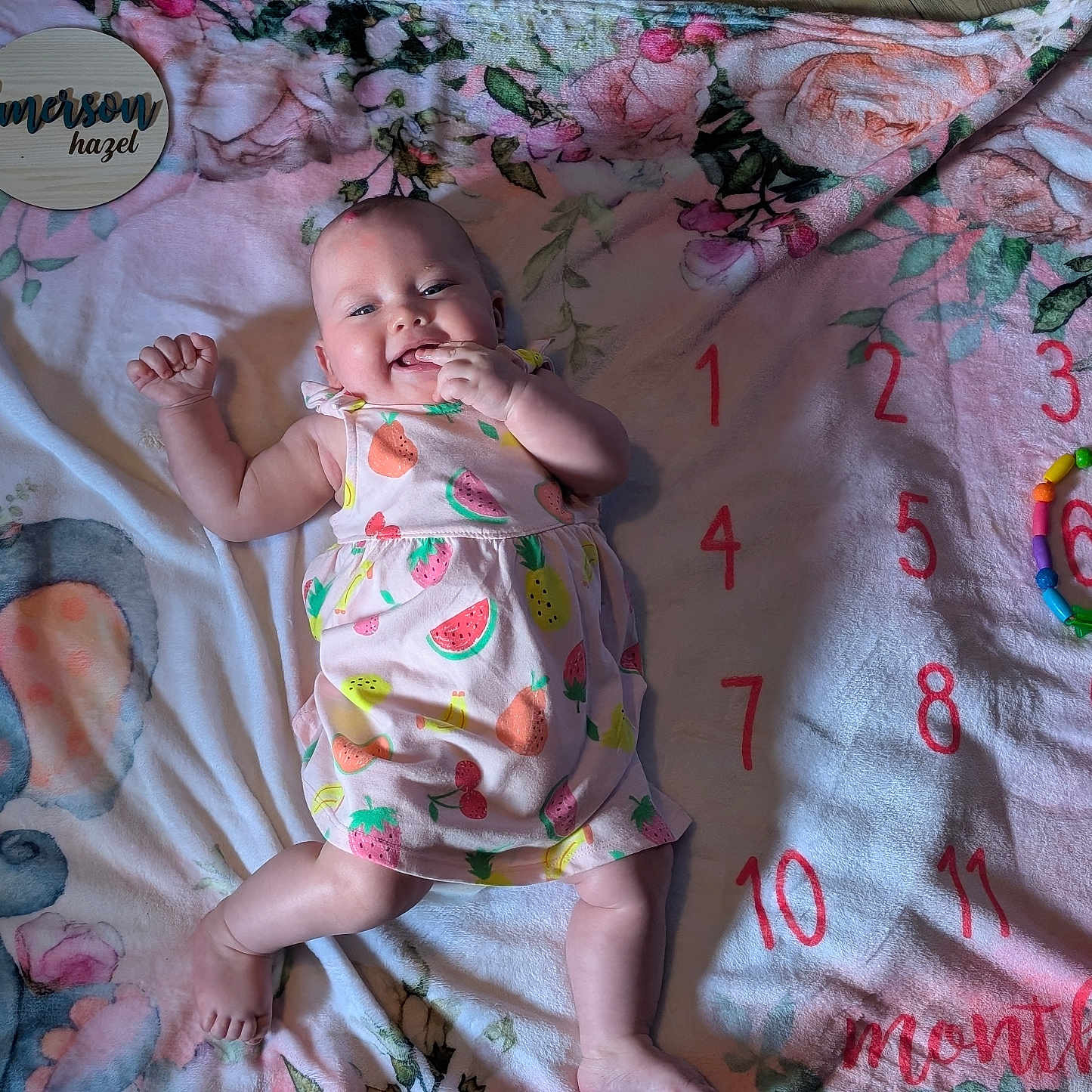 Emerson joined the competition — help win amazing prizes! baby, blanket, child, colorful, cute, dress, elephant, floral, fruit_pattern, happy, indoors, infant, lying_down, months, numbers, playful, skin, smiling, toy, wooden_sign