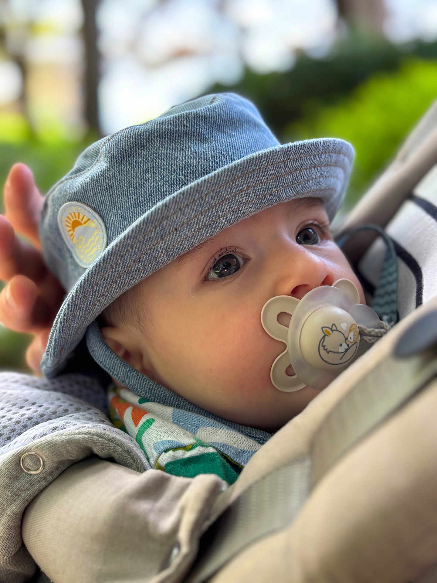 Elias participe au concours pour gagner de l'argent avec cette photo : baby, denim_hat, pacifier, close_up, face, outdoor, child, cute, infant, portrait, hat, apparel, headwear, peaceful, colorful, fabric, nature, soft_focus, young_child, expression