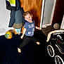 Albie is registered to the contest to win money with this photo: child, barefoot, blue_shirt, black_pants, soccer_ball, jacket, coat_hook, wooden_door, carpet, stroller, indoor, smiling, playful, floor, toy, clothing, person, happy, room, home