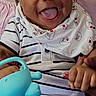 baby, bib, chair, child, curly_hair, face, family_photo, hands, happy, indoor, infant, laughing, legs, pink_blanket, portrait, seated, smiling, striped_clothing, toy, watering_can