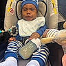 baby, infant, child, car_seat, carriage, striped_clothing, hat, bib, bottle, plush_toy, stuffed_animal, pacifier_clip, socks, seated, portrait, indoors, vehicle, travel, alert, cute