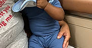 Baby Jojo is registered to the contest to win money with this photo: baby, child, infant, sitting, lap, caregiver, portrait, indoor, blue_outfit, bib, hand, chewing, curious, serious_expression, black_socks, furniture, bench, warm_lighting, candid, family