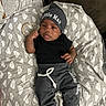 baby, beanie, black_clothing, blanket, child, cozy, crib, facial_expression, feet, hands, hat, heart_pattern, indoor, infant, little_man, lying_down, newborn, photography, portrait, sleepwear