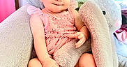 Ember is registered to the contest to win money with this photo: baby, child, pink_dress, headband, plush_toy, bunny, armchair, couch, blanket, curtain, indoor, cute, smiling, sitting, person, portrait, soft_toy, toddler, happy, cozy