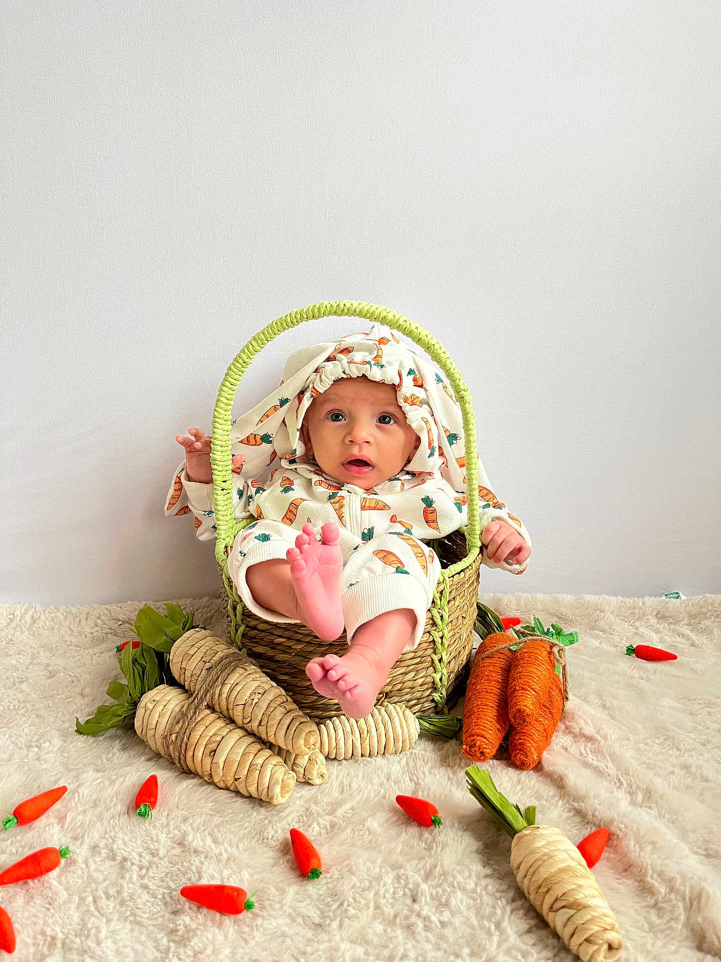 Xyleek joined the competition — help win amazing prizes! baby, child, basket, carrot, plush_carrot, carpet, cute, infant, clothing, decor, foot, hand, face, indoor, white_wall, woven, playful, soft, sitting, curious