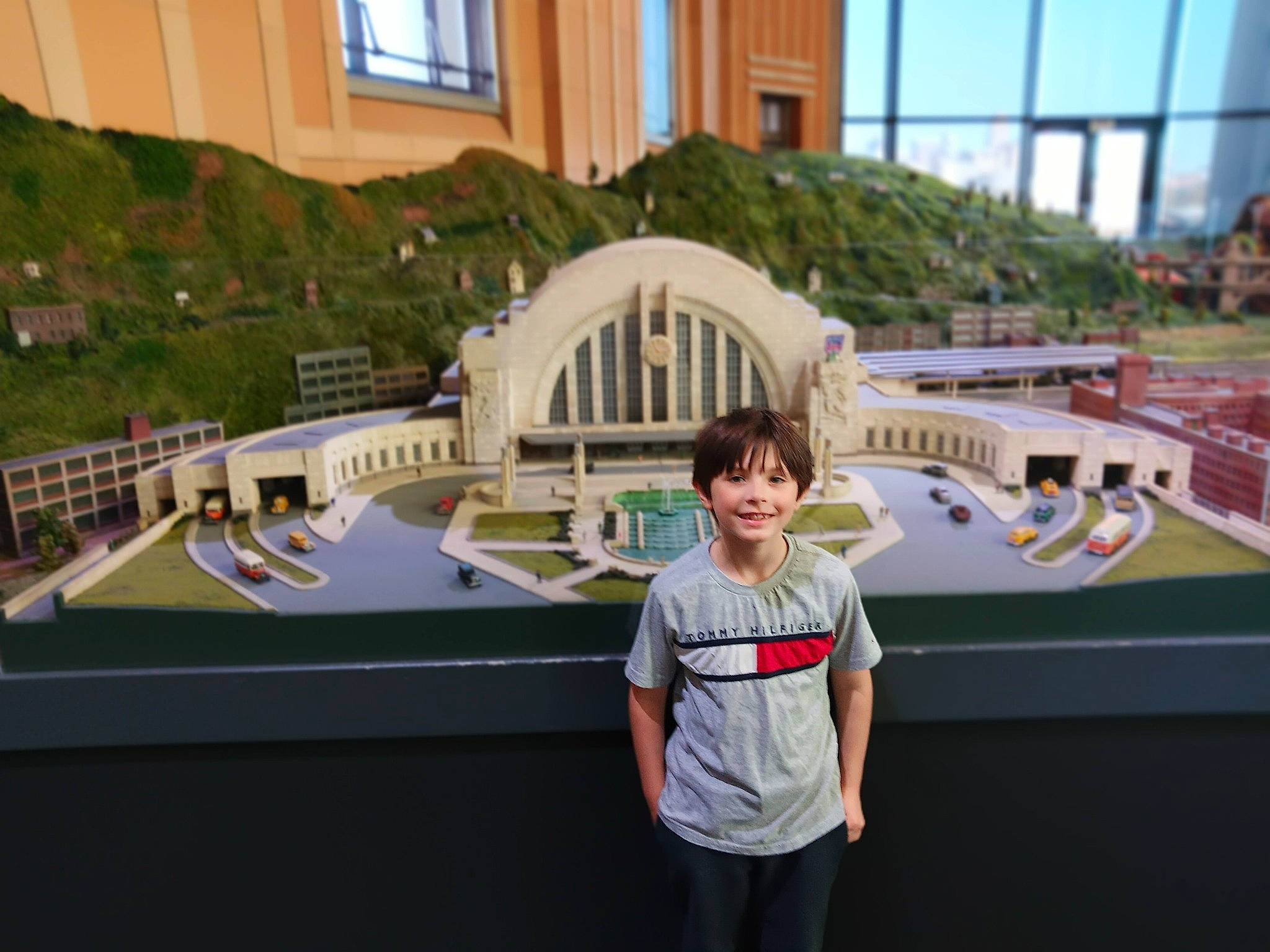 Tommy is registered to the contest to win money with this photo: city, fun, joy, leisure, luxury_vehicle, mixed_use, person, recreation, roof, room, scale_model, shorts, sleeve, smile, t_shirt, tourism, tourist_attraction, toy, travel, urban_design